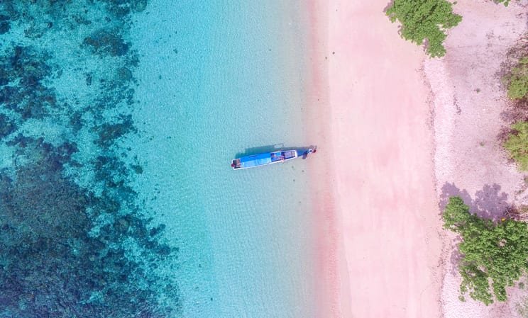 Blue boat docked on the pink sand on the island of Komodo, Indonesia