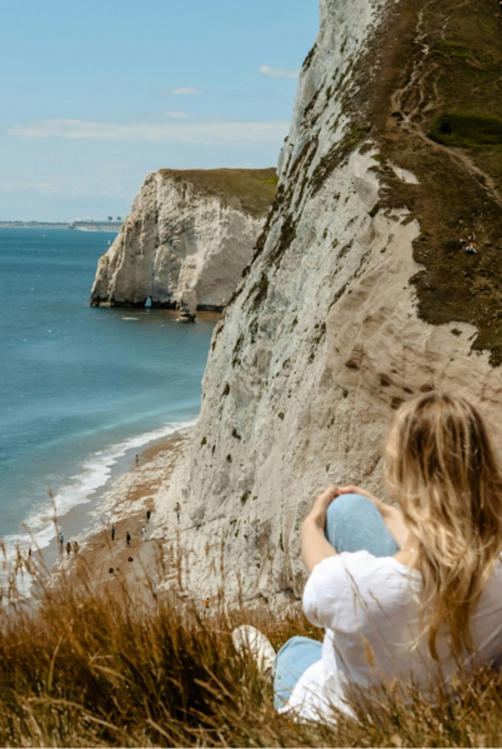 Woman sits looking at Durdle Door Dorset, United Kingdom