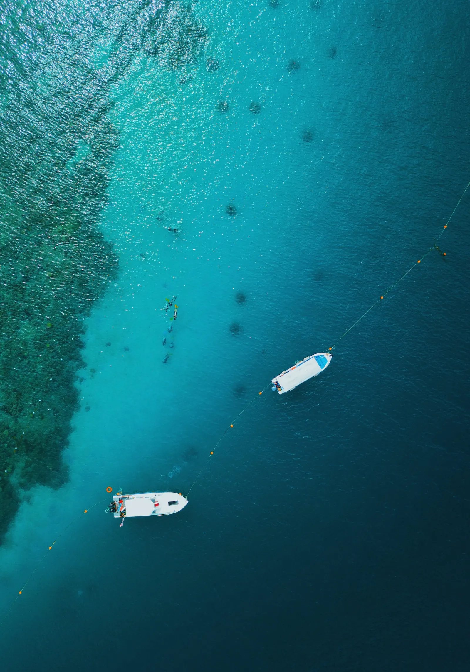 Corals and boats on blue water in Borneo